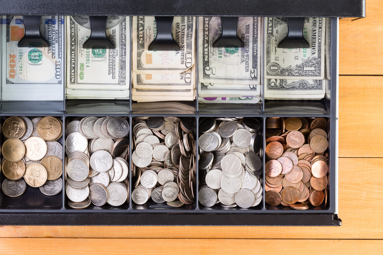 Open cash register drawer with cash and coins