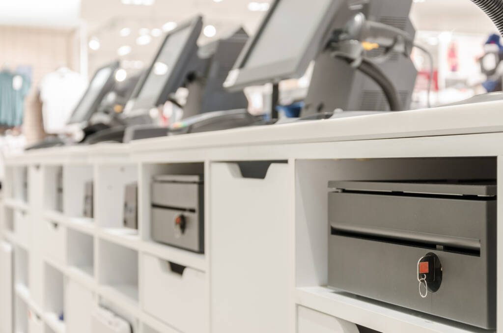 Row of closed retail cash registers in a store