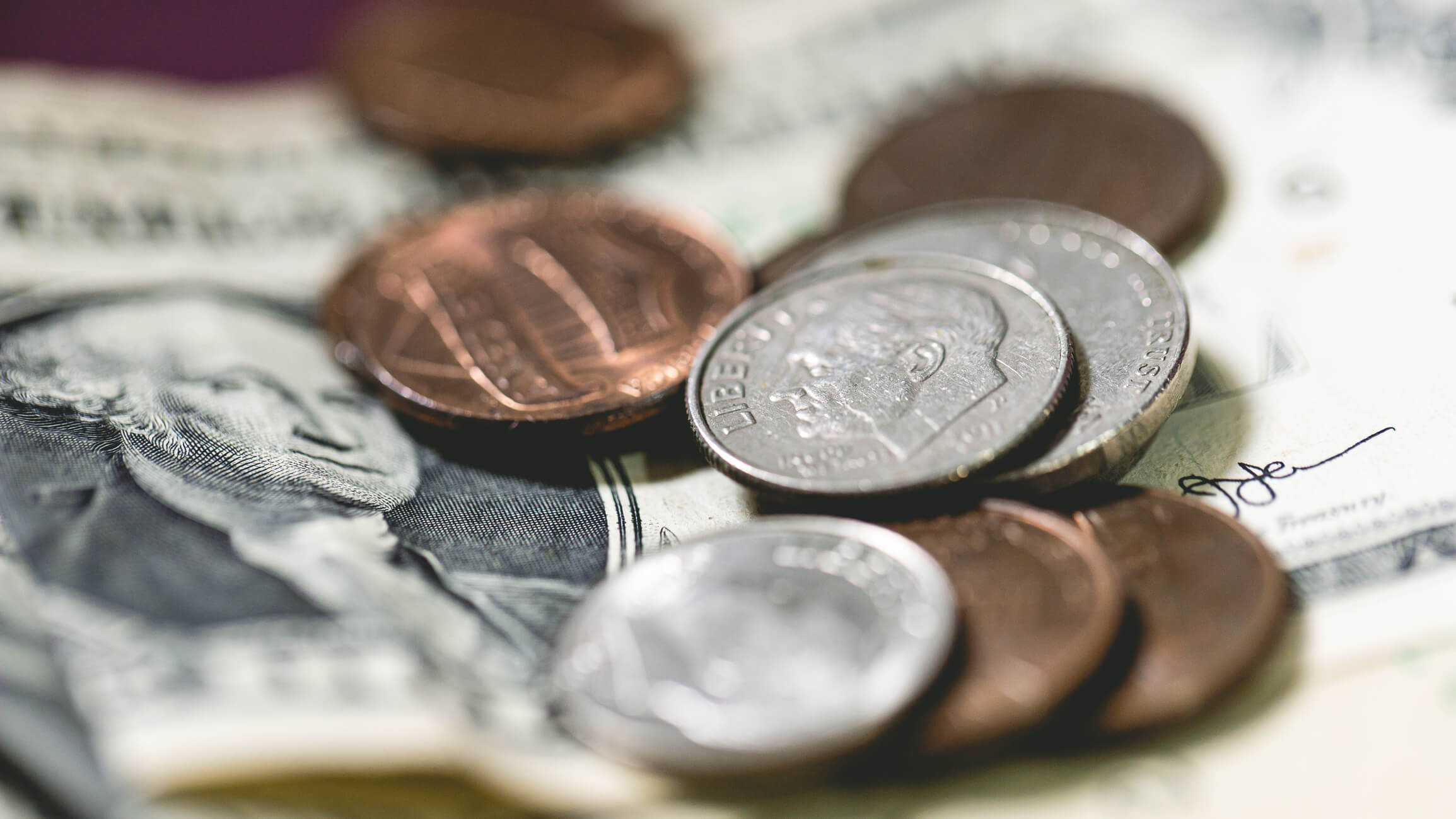 Zoomed-in photo of dimes and pennies on top of a dollar bill