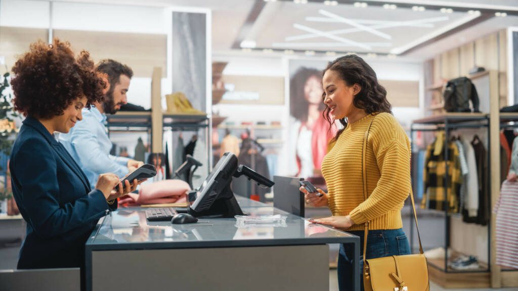 Woman making a purchase at a retail store with another woman assisting her.