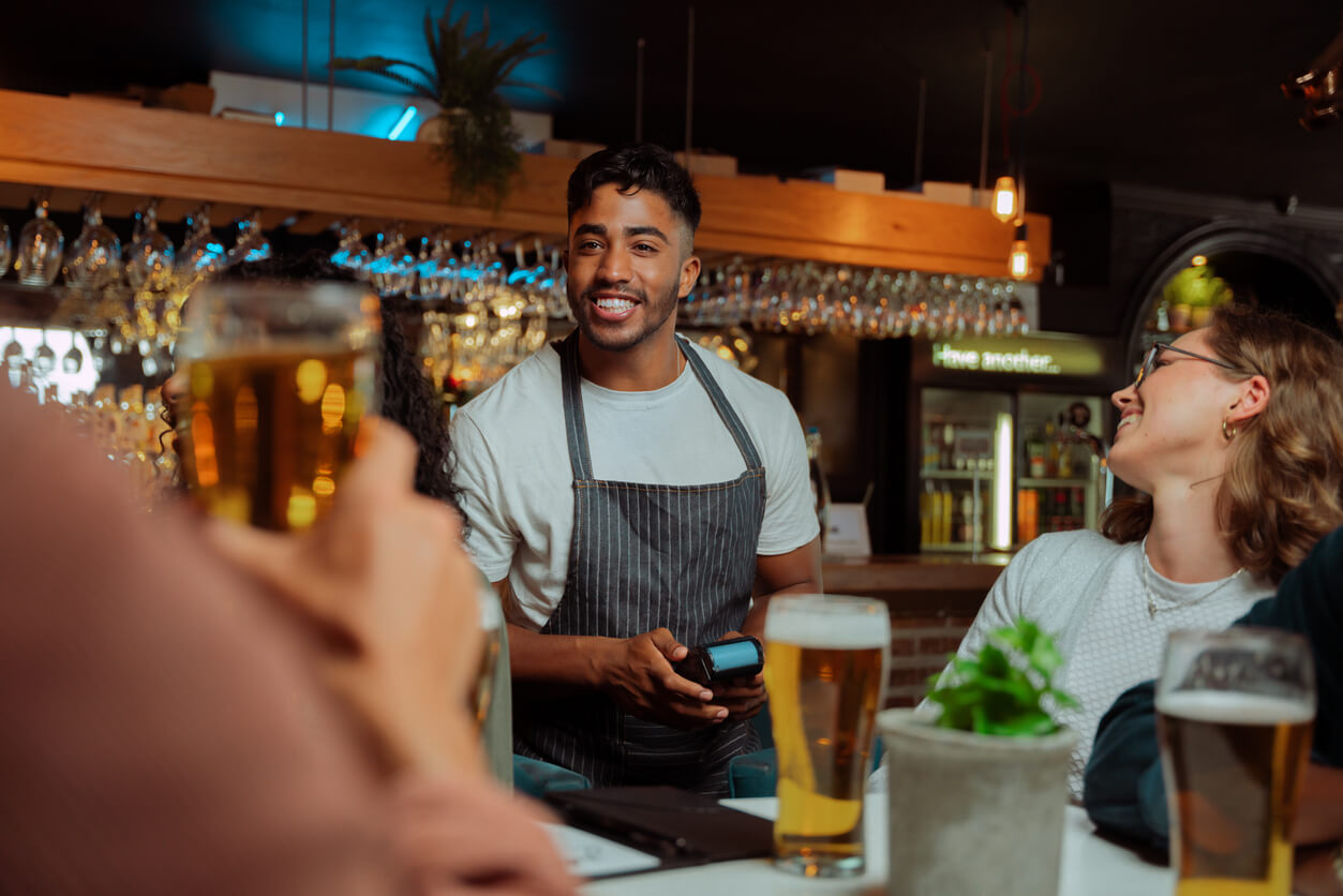 Server checking if table is ready to pay with credit card reader in his hand