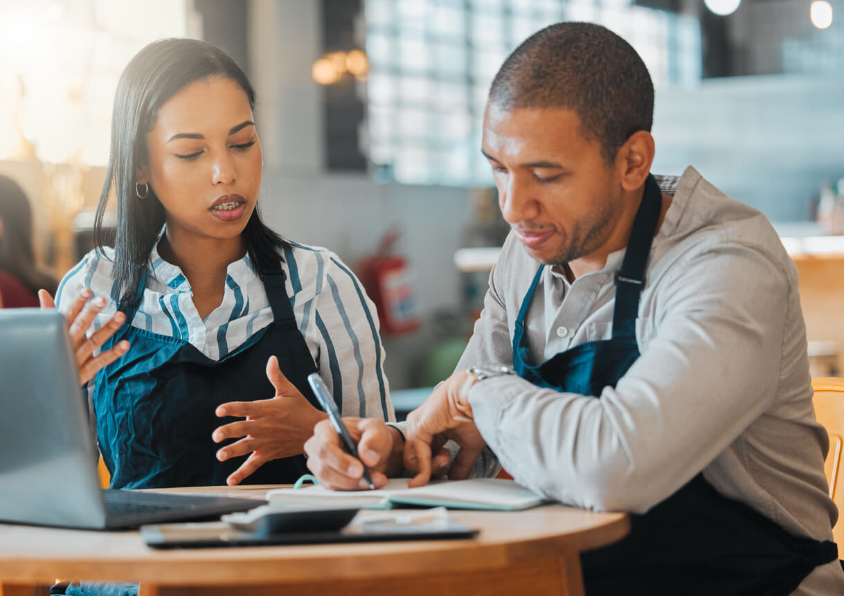 2 restaurant managers sitting and discussing paperwork to manage restaurant labor costs