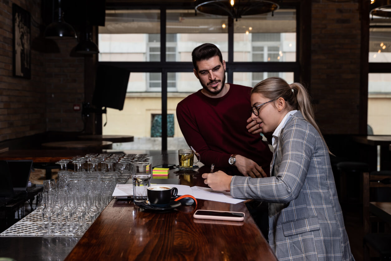 manager and server talking and going over paperwork to manage restaurant labor costs