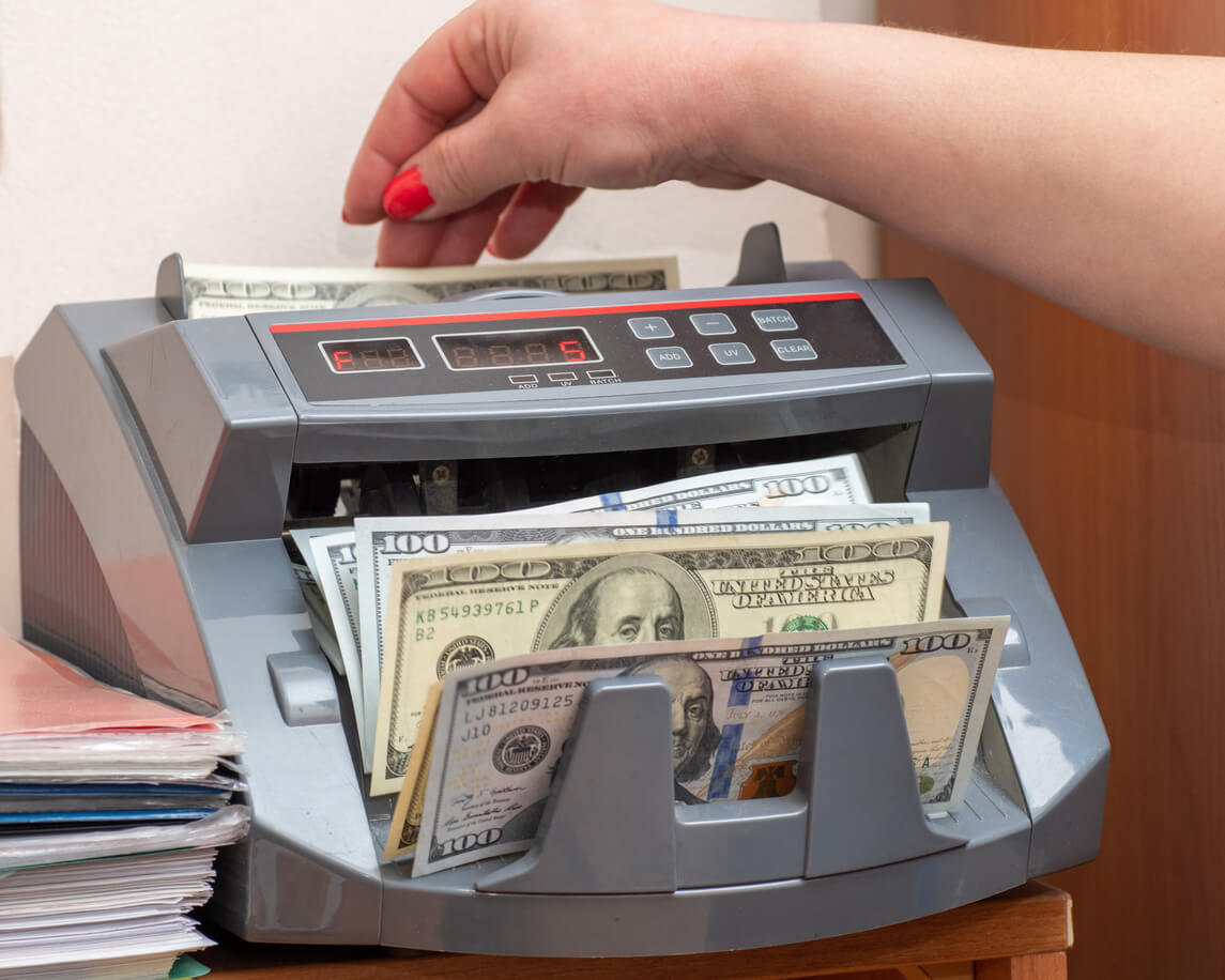 person using a money counting machine for dollar bills