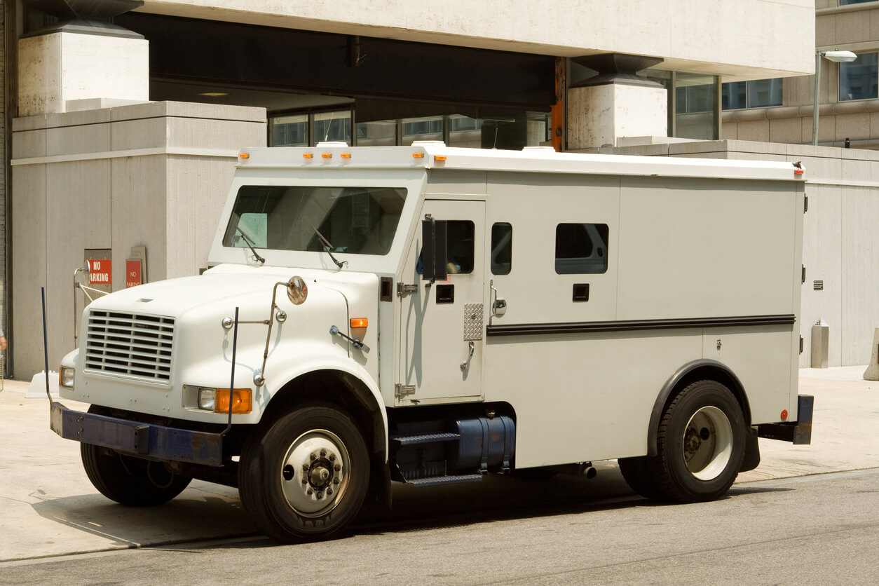 Beige cash in transport armored truck outside a building