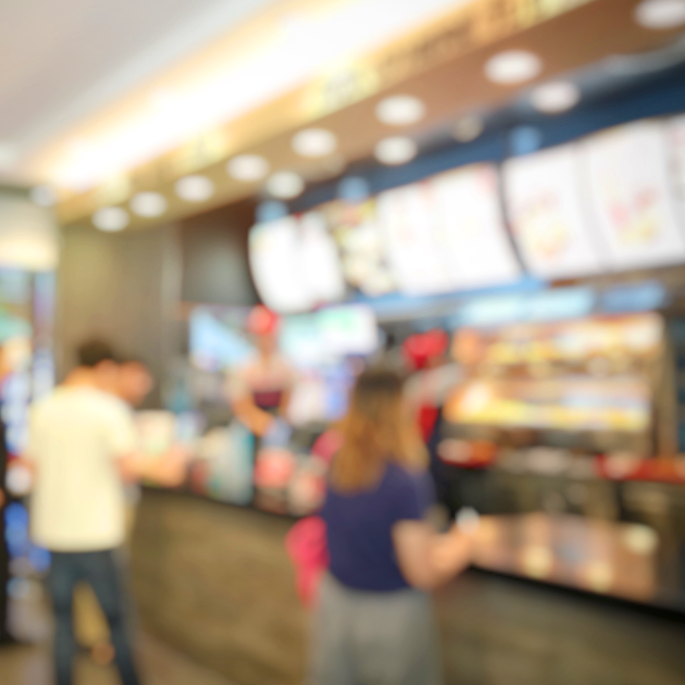 blurred image of people standing at a fast food counter