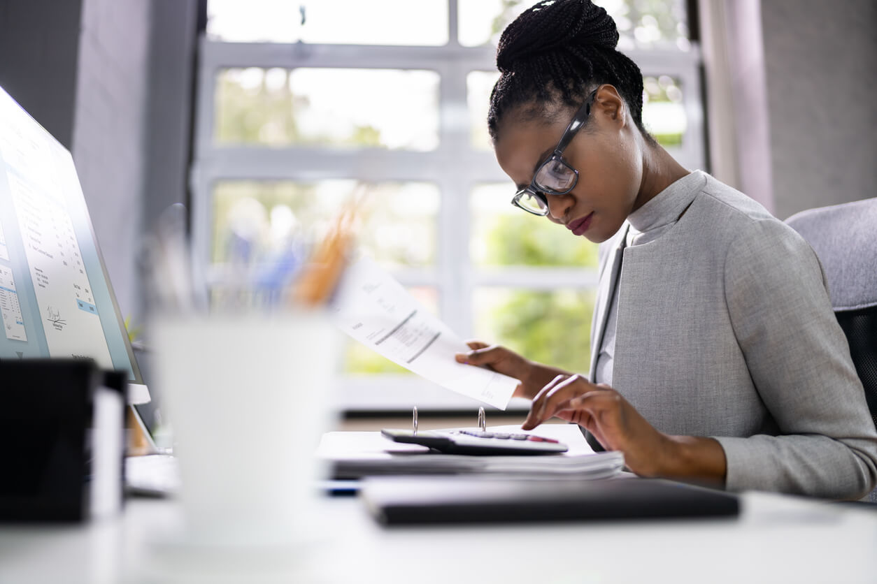 woman reviewing paperwork and using a calculator