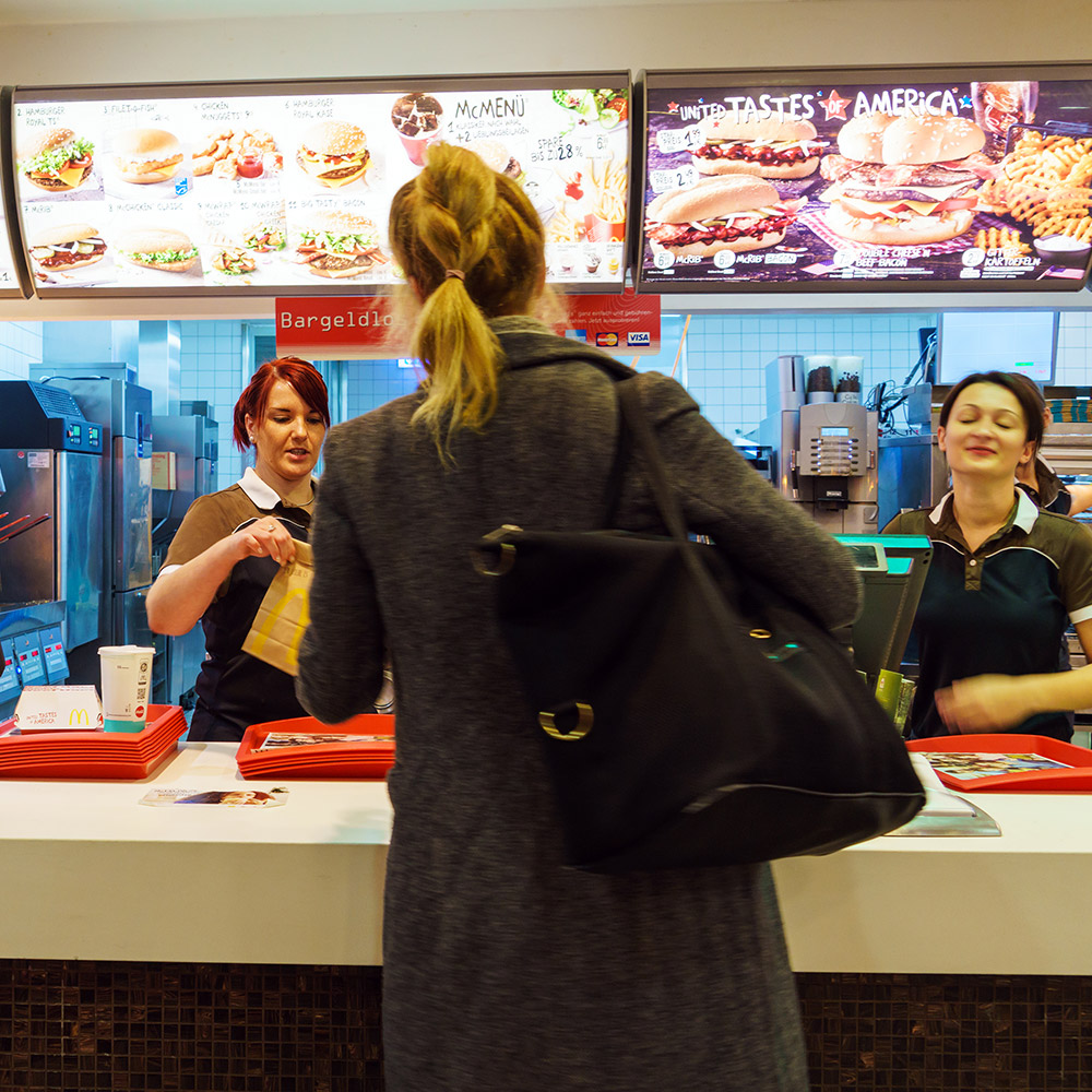 A person standing in front of a counter at a fast food restaurant waiting to order