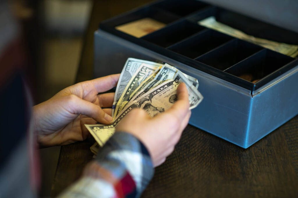 person counting cash at a regsiter