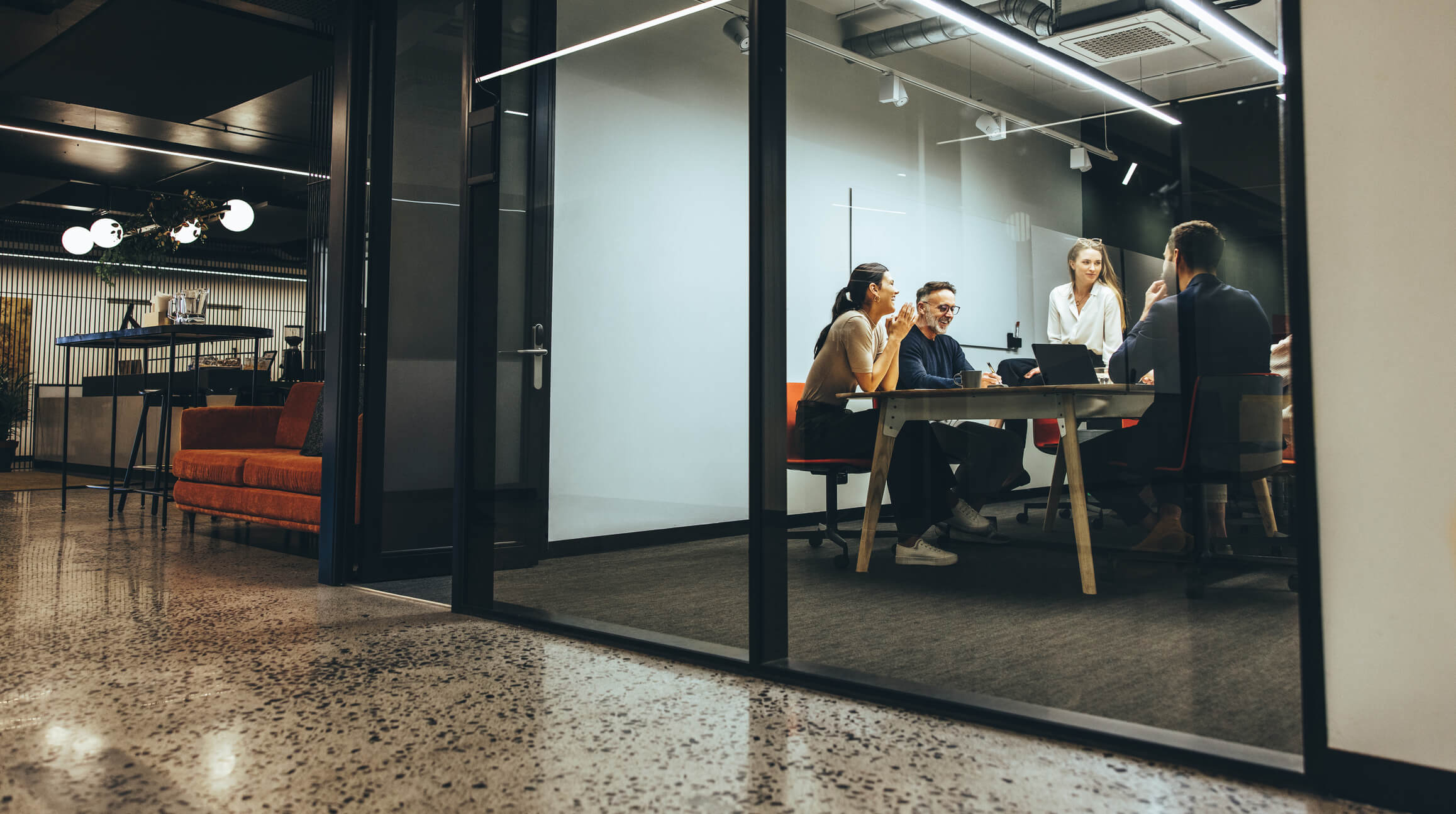 a group holding a meeting in a private office room with glass windows