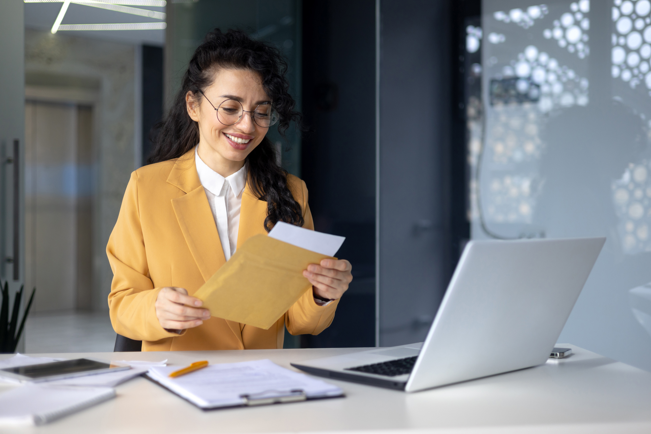 Successful woman inside office at work businesswoman received postal envelope letter notification with good news, female worker celebrating victory and good results achievement at workplace.