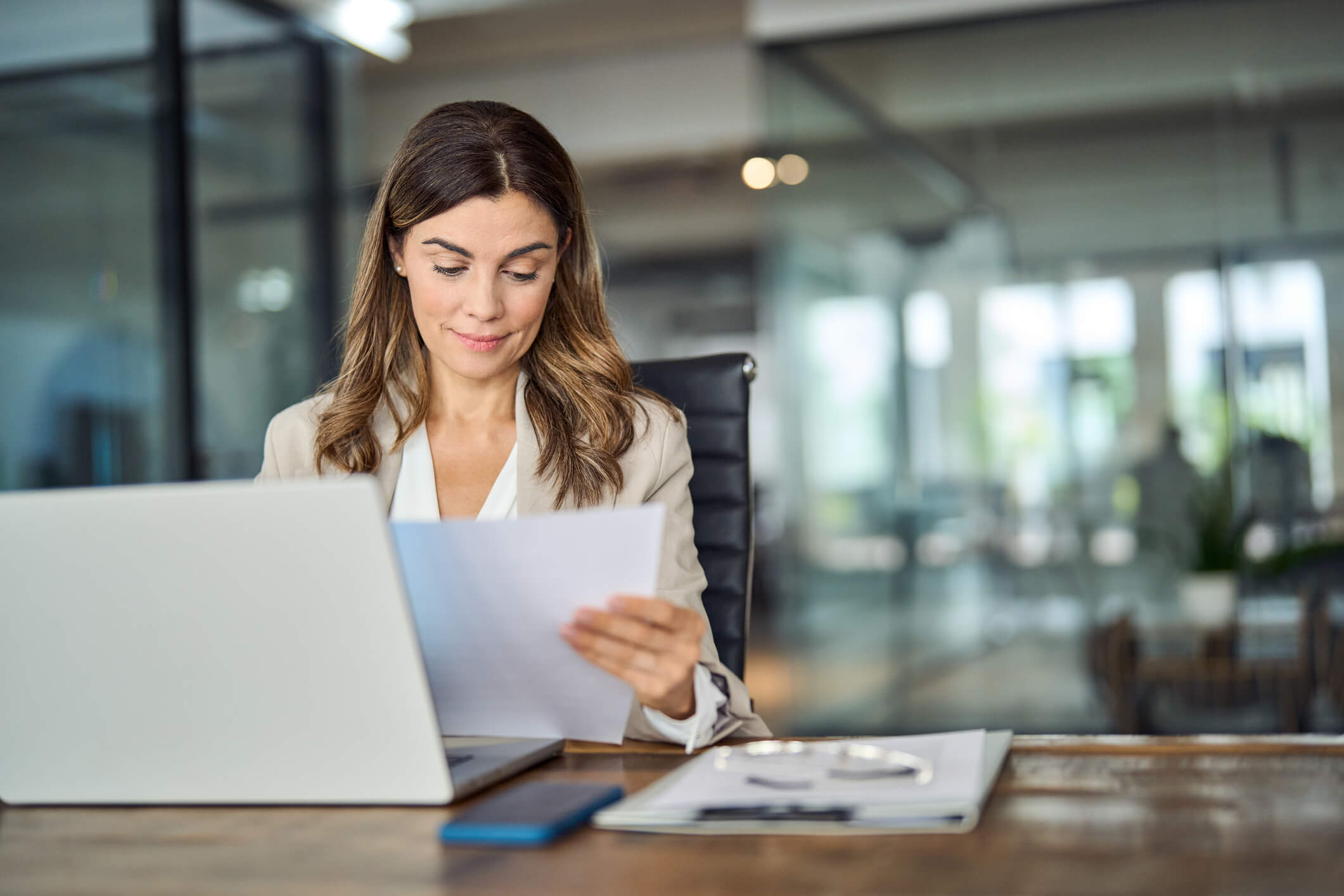 woman reviewing documents while working on a laptop