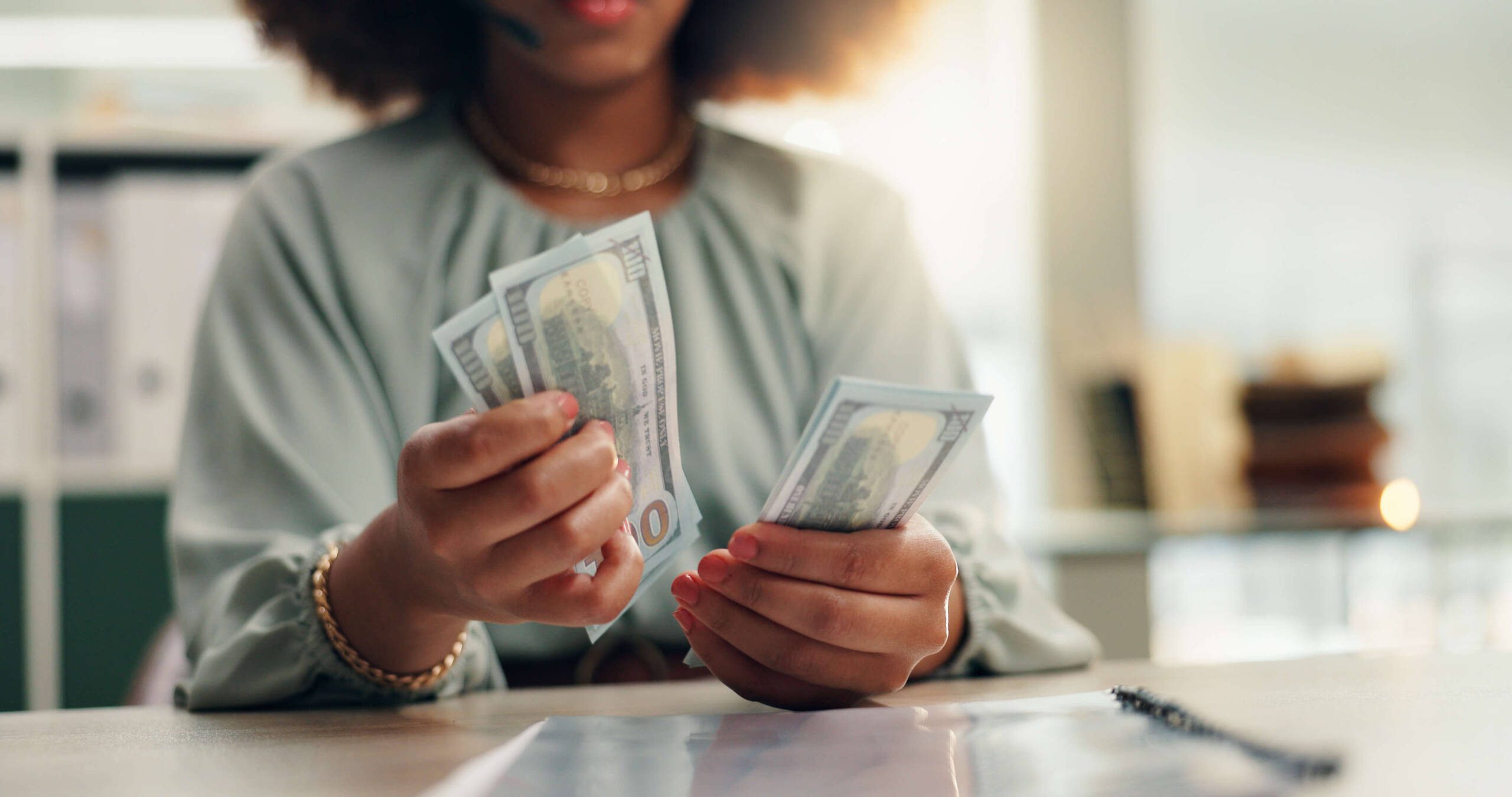 Black woman counting hundred dollar bills