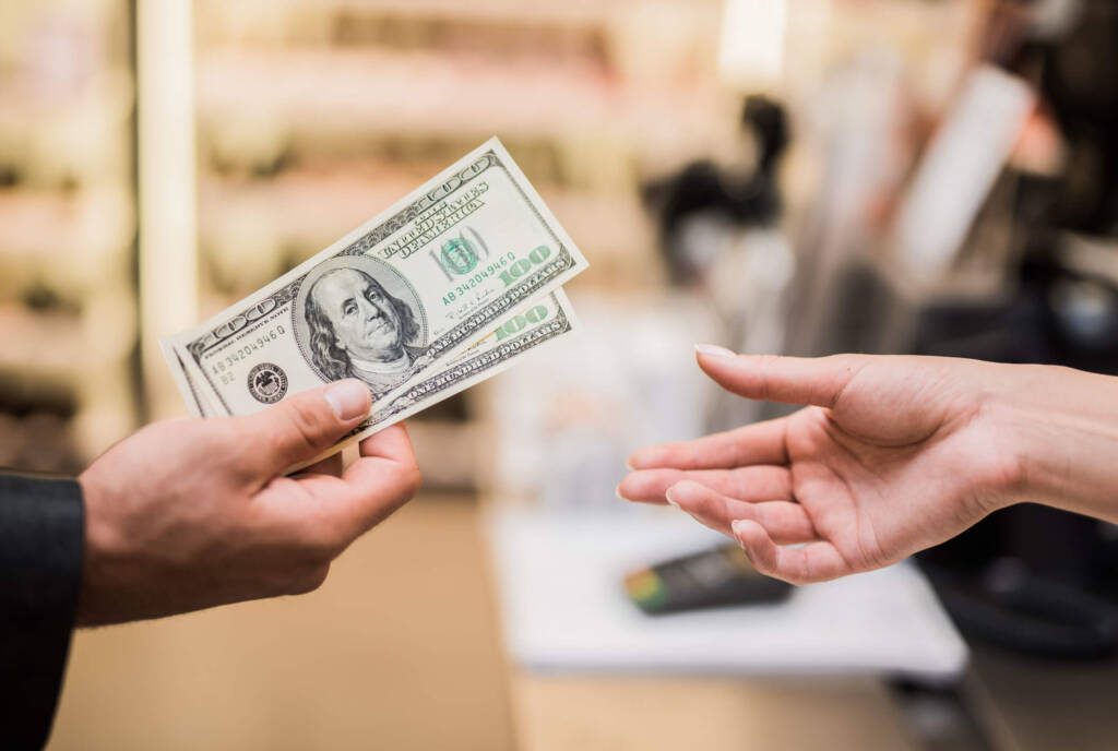 someone paying in cash to a cashier who will manage the cash