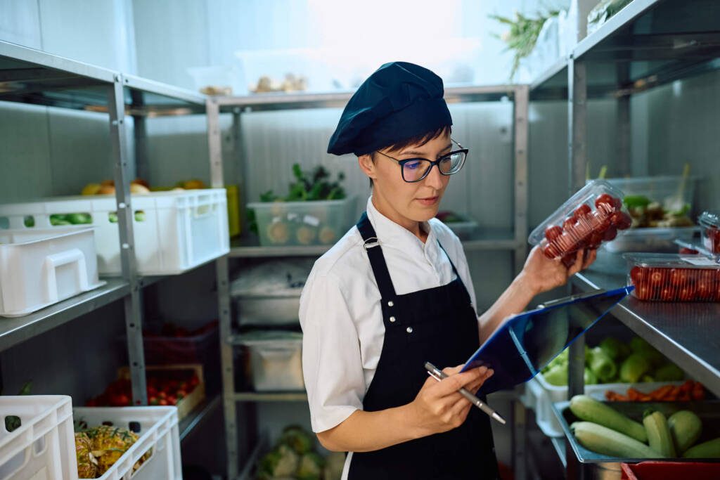 a chef in a restaurant fridge checking on local ingredients